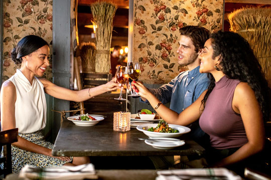 3 people clink glasses at a restaurant
