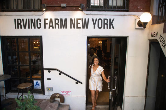 A woman in a yellow striped dress walks out of Irving Farm New York