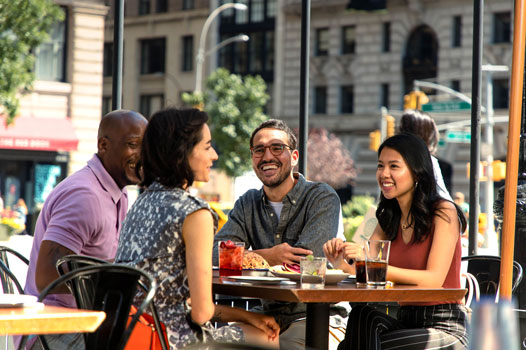 4 friends enjoy an outdoor sidewalk patio at a New York City restaurant