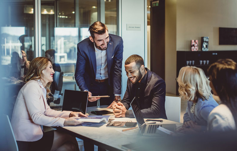 A group of young professionals smile and work together in a conference room